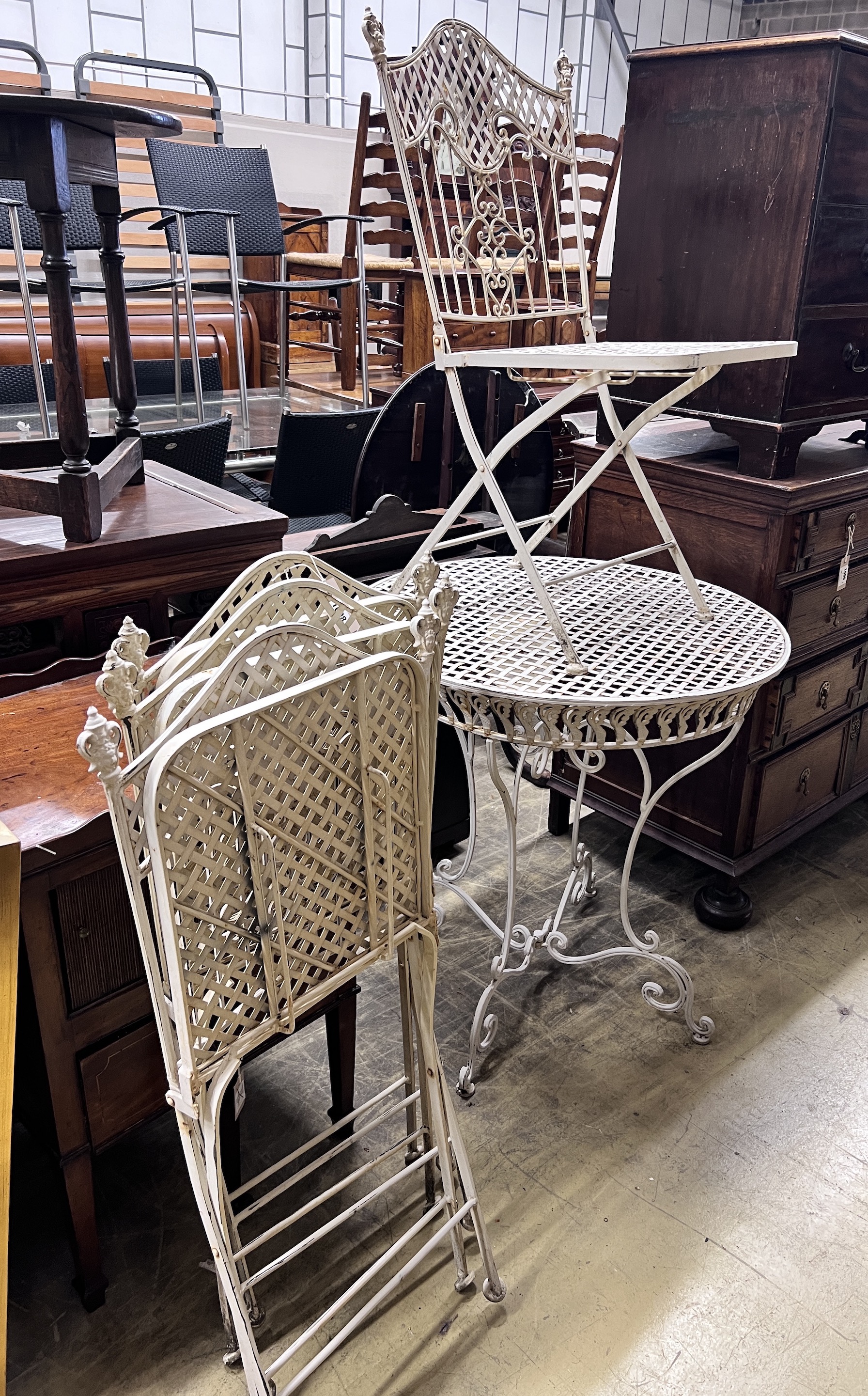 A white painted wrought iron garden table and four folding chairs